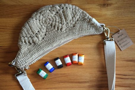 Karottenförmige Tasche mit grünen Blättern und orangenem Band zum Tragen.